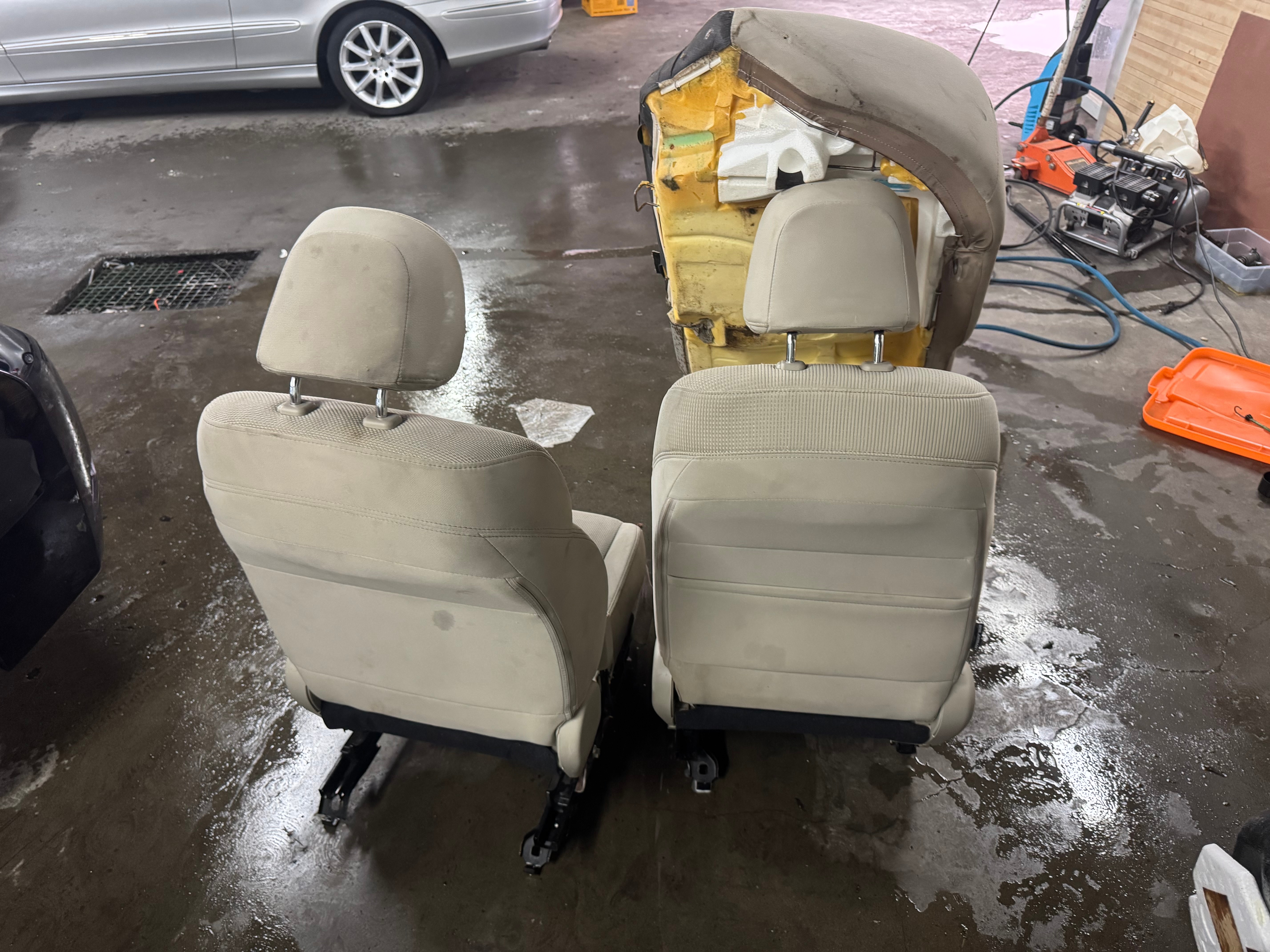 Beige car seats removed from a vehicle and being cleaned in the shop