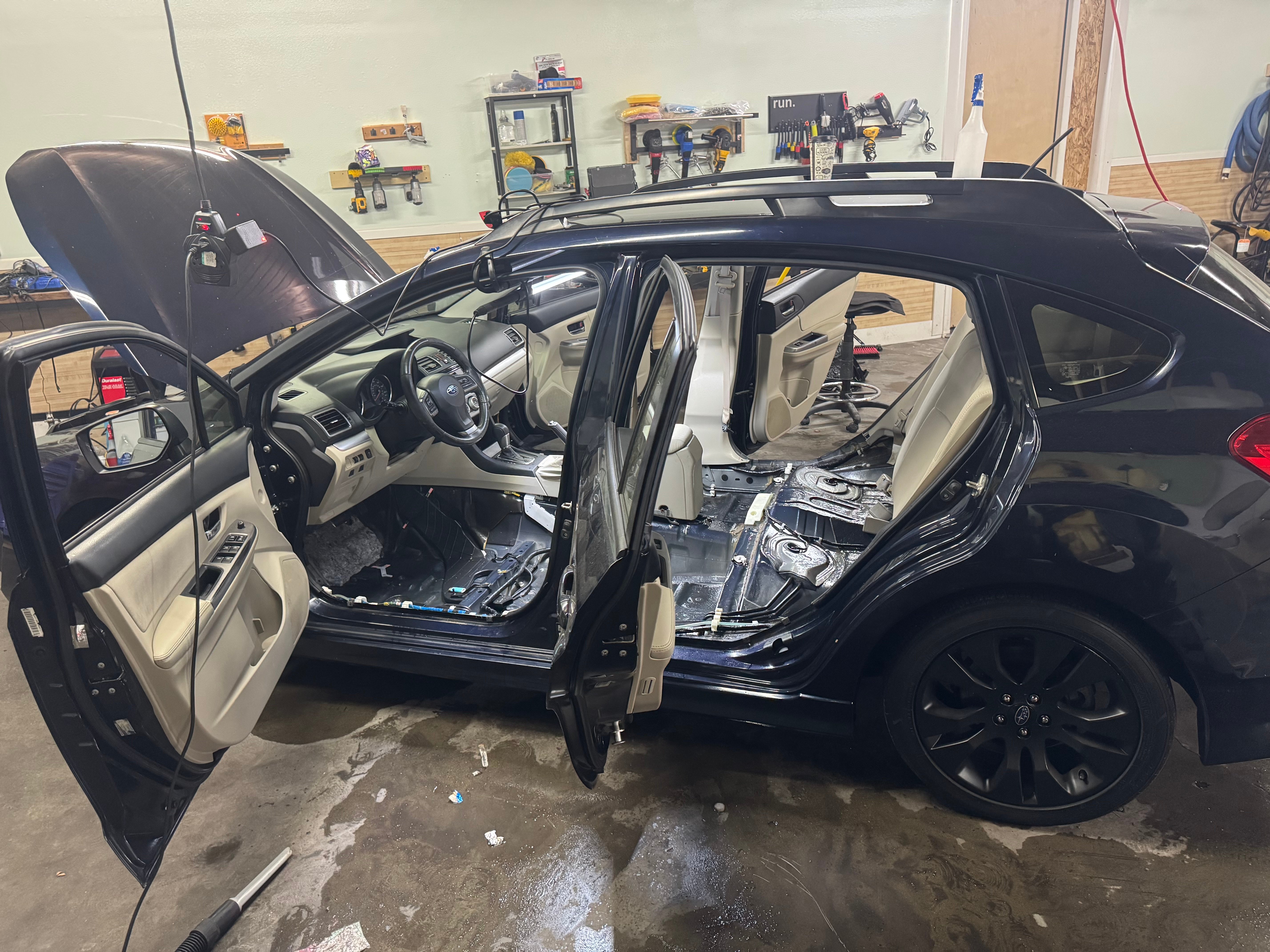 A dark blue Subaru with doors open and seats removed for a full interior detail